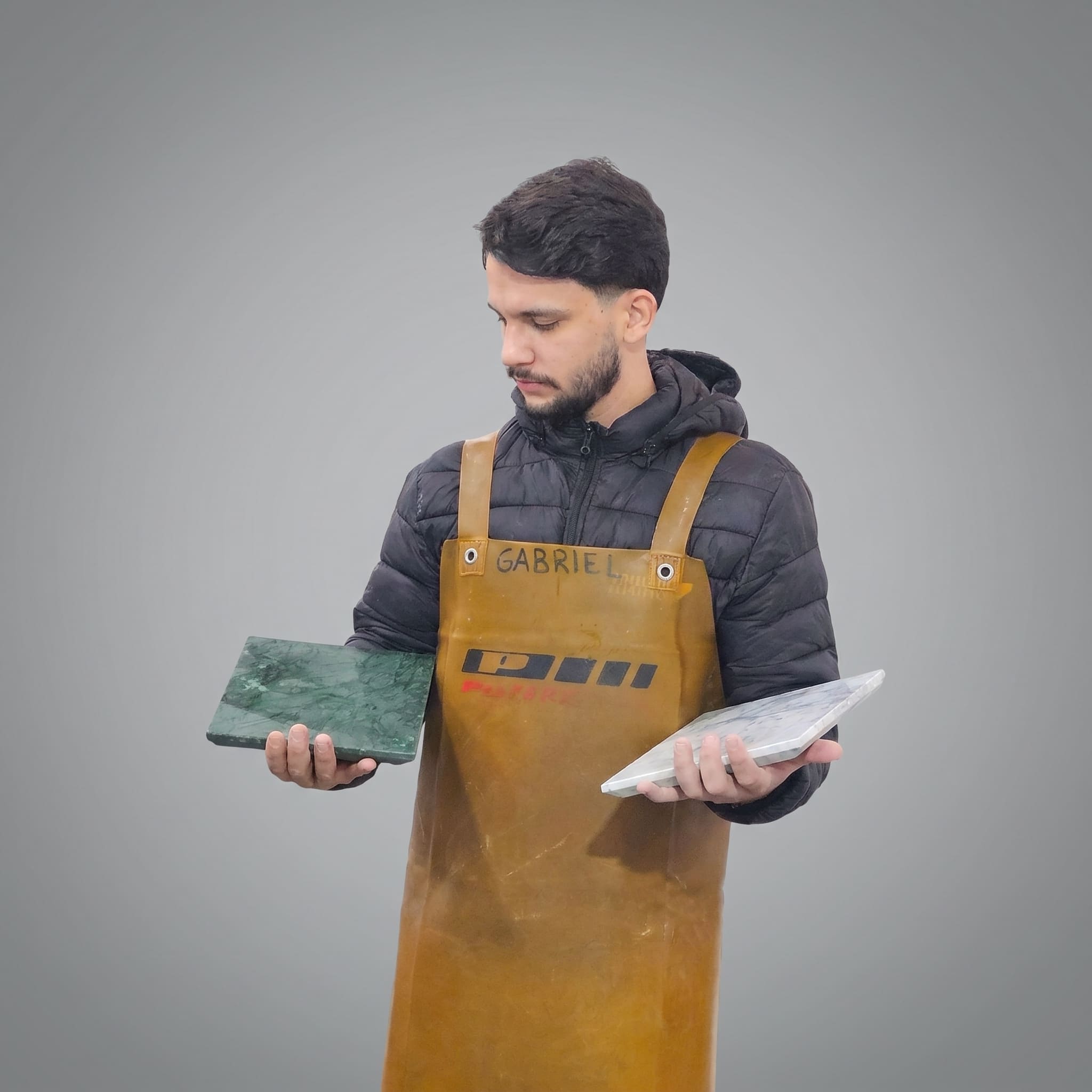 Gabriel da Silva, artesão da D’Altare, segurando duas peças de mármore esculpidas à mão na oficina em Penha, Santa Catarina